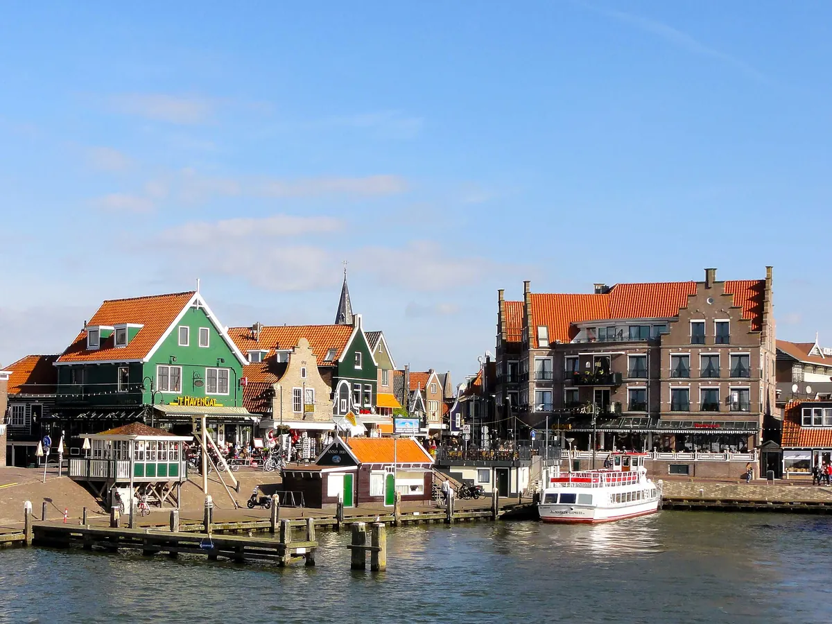 De haven van Volendam met groene houten huizen en een rondvaartboot